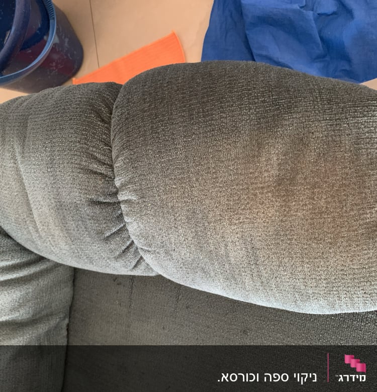 ספה אפורה עם דלי כחול ומטלית כתומה